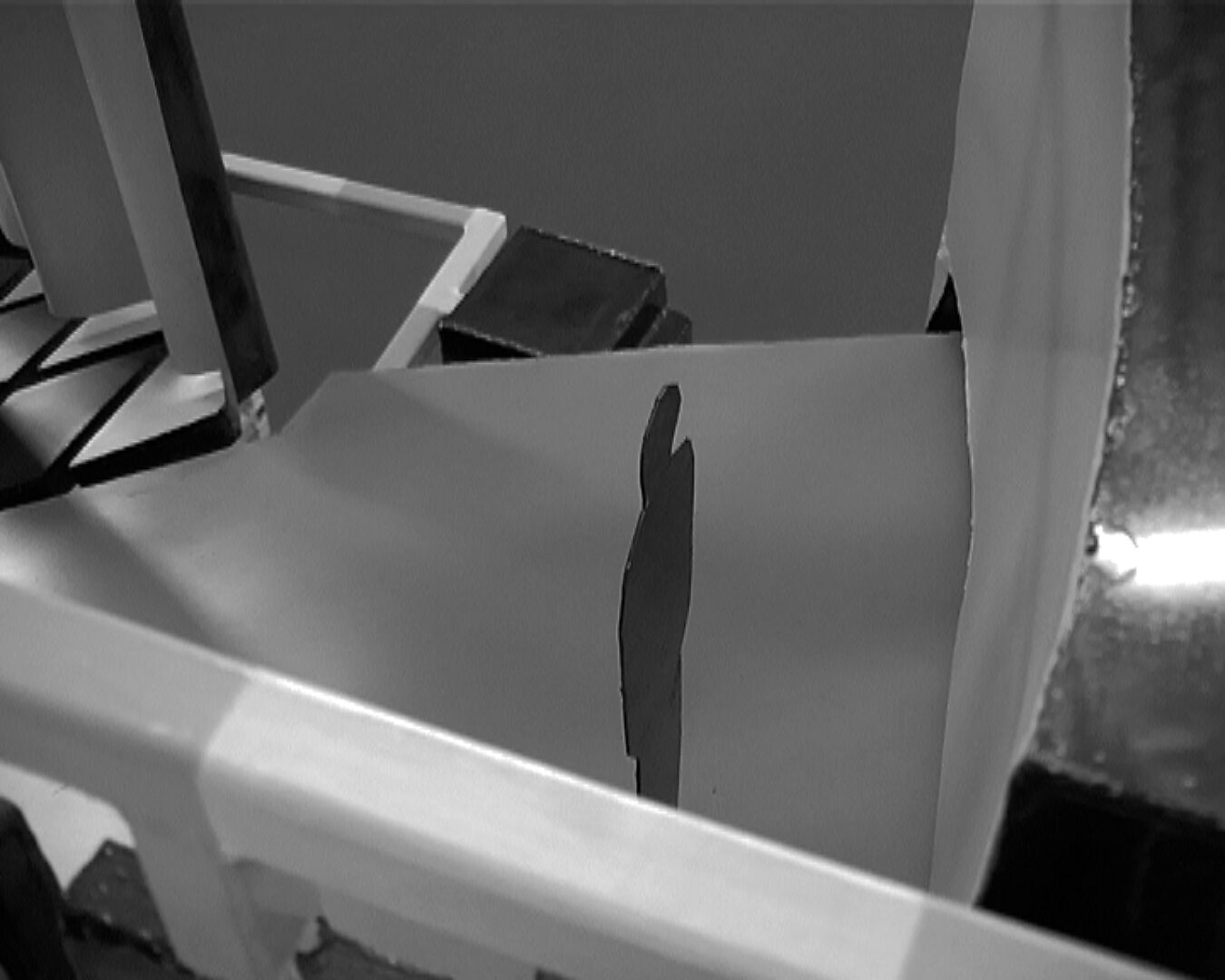 Big Brother in storing — videostill van het interieur van de installatie waarin een schaduwachtige menselijke figuur verschijnt, alsof het lichaam wordt gemeten of gefilterd door de constructie.