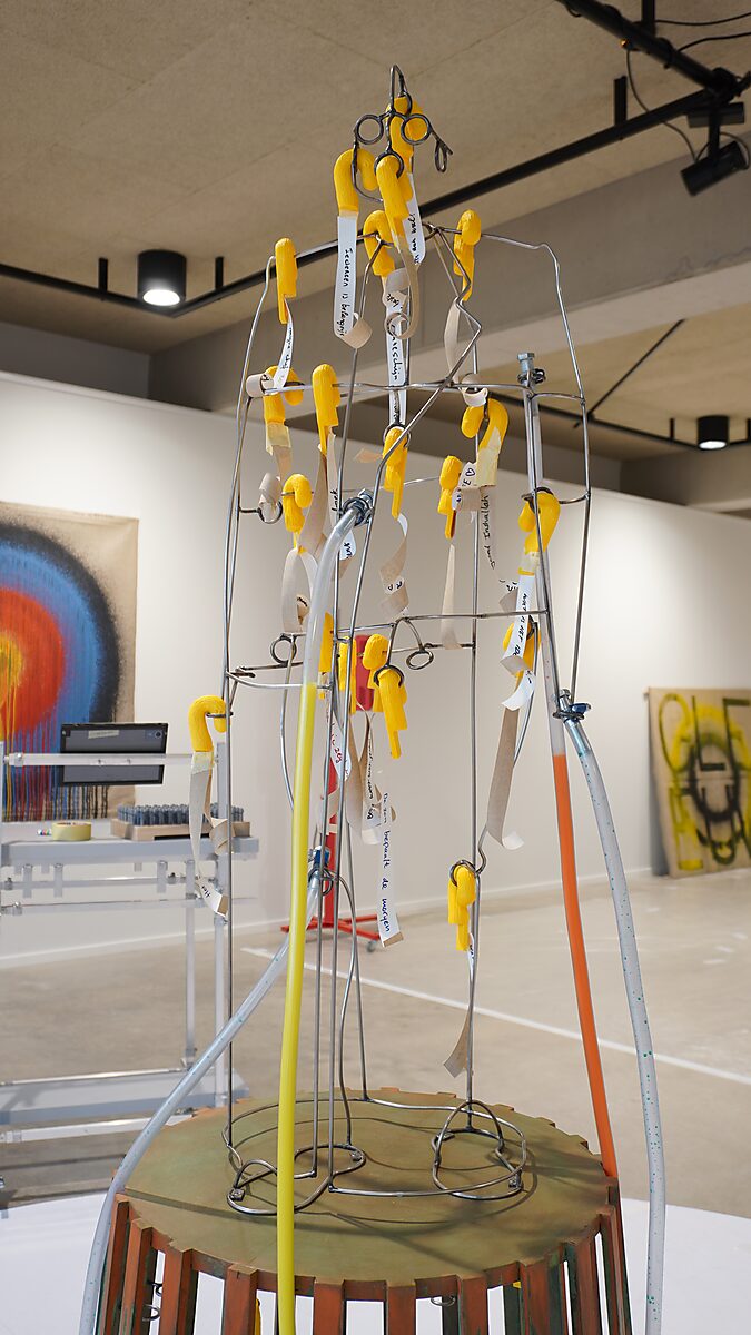 Sfincterman with Colour Tentacles — detail: close-up of the tubes connected to the metal structure, with clamps and connection elements visible.