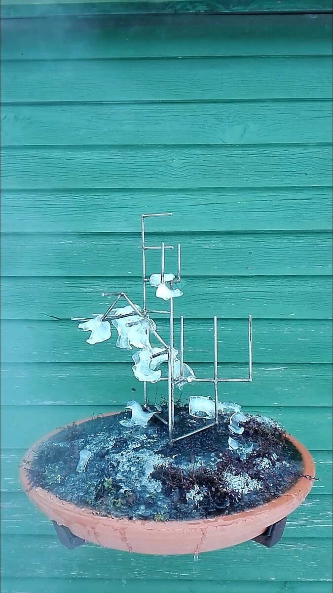 Entropic Sculpture No. 1 — videostill of the sculpture in winter with largely melted ice and ice remnants around the metal armature on the frozen soil.