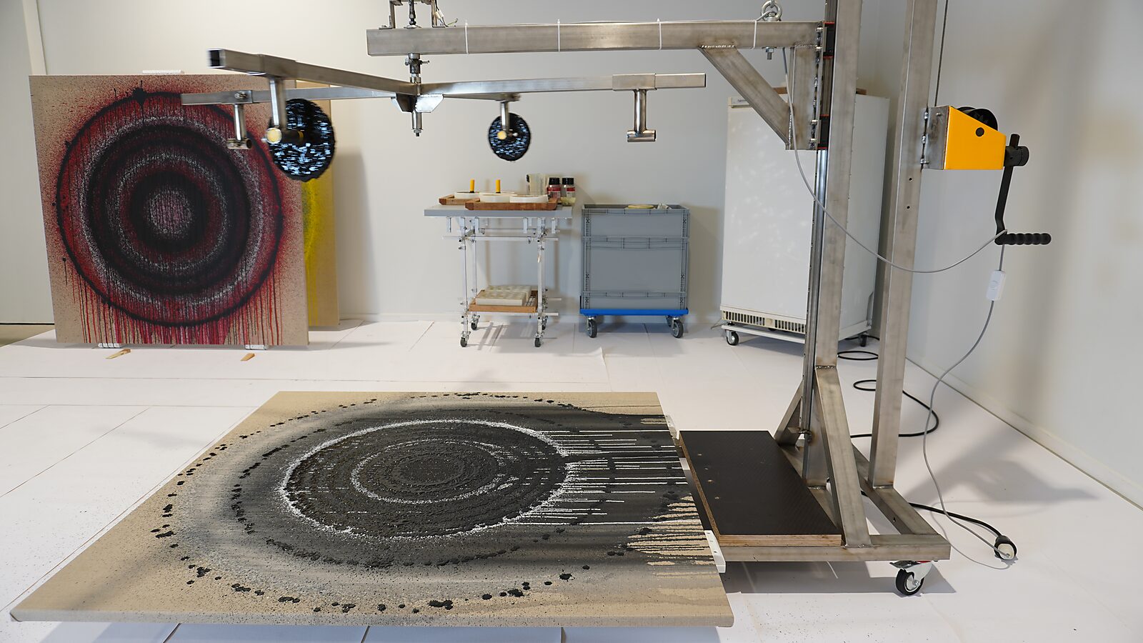 Melting Targets No. 4 — working installation with adjustable metal armature above a canvas where black concentric paint rings form, Transformation Studio No. 1: warm or cold, CC De Adelberg, Lommel.