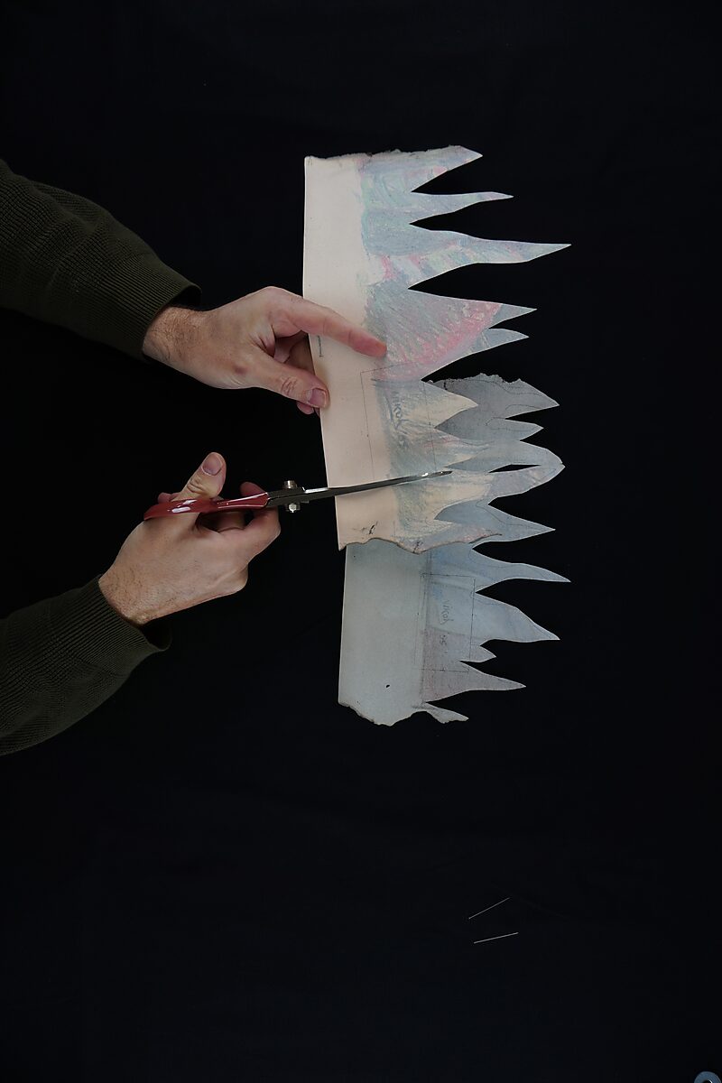 Benoemens-waardvlinders — Naming–Value Butterflies — proces tekening: Hangende man (1995) — handen knippen een smal stukje papier met een naamlabel uit terwijl de rest van de tekening erboven hangt.