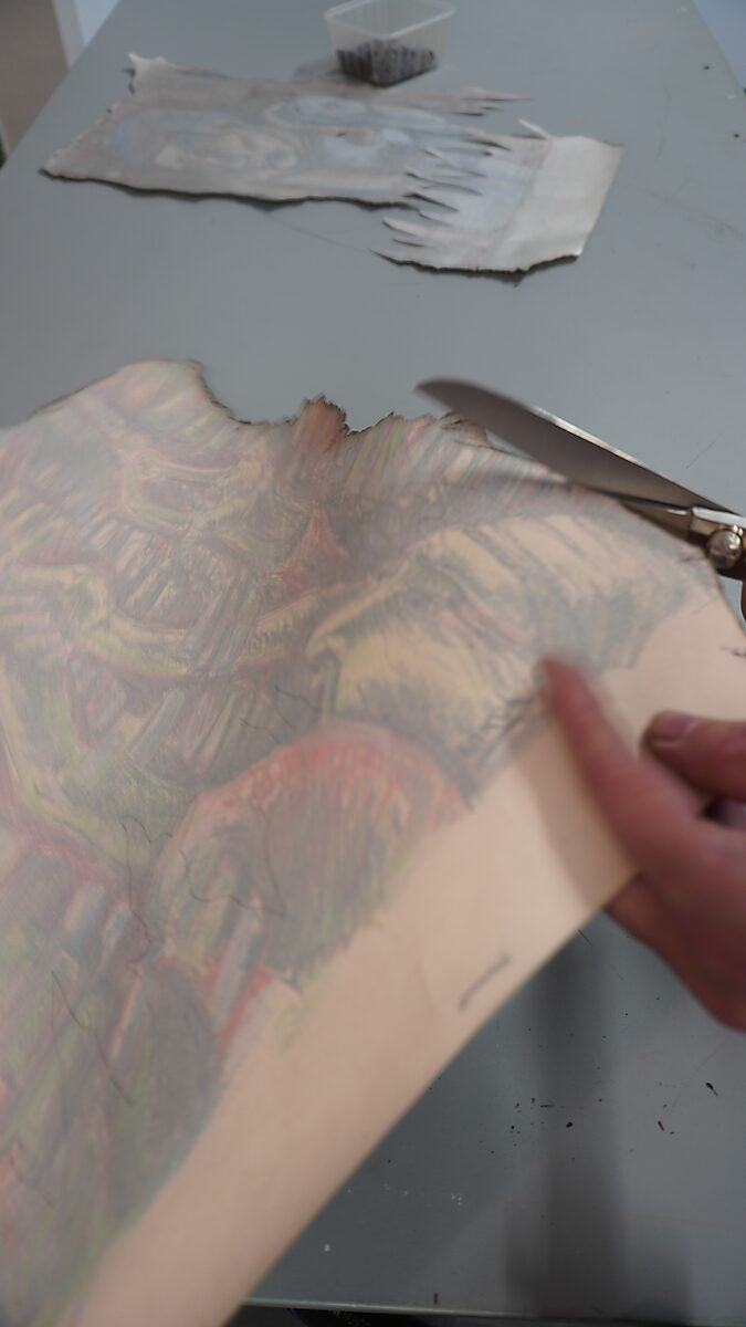 The Divider — process photo: cutting flame-shaped edges into a drawing on a worktable.