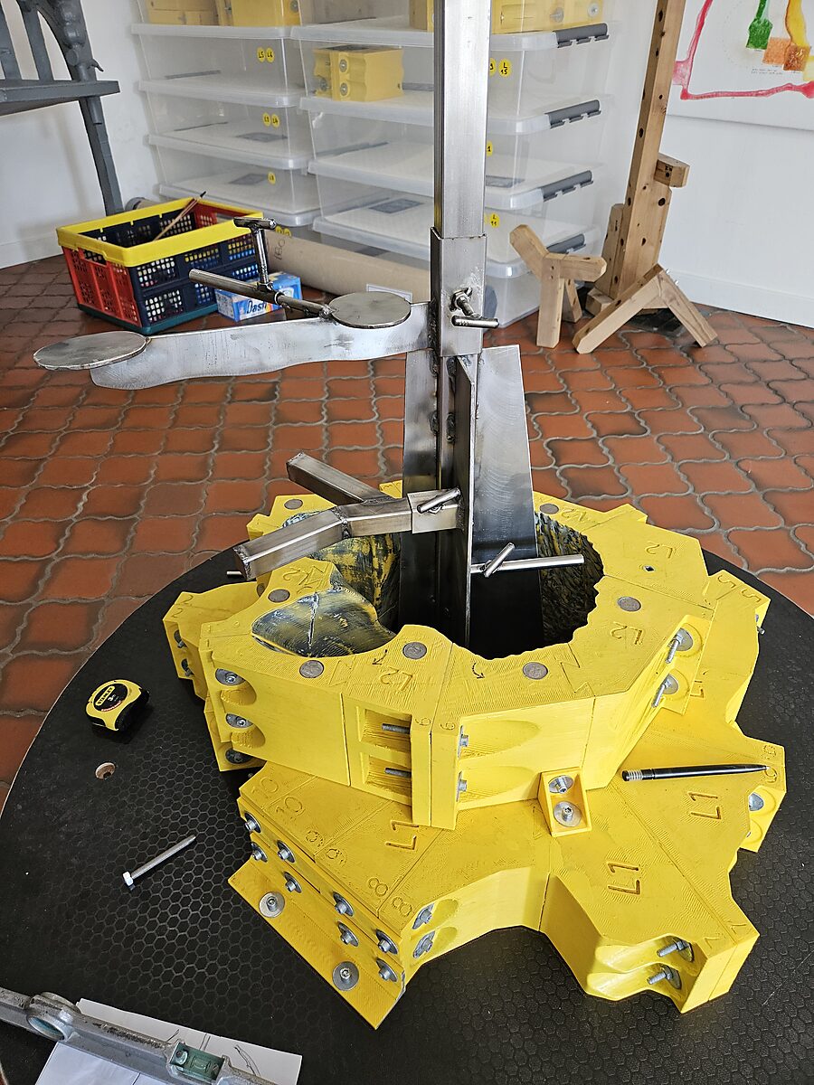 St. Sebastian with Birds No. 4 — detail photo of the stainless steel armature being assembled through a ring of the yellow modular mould.