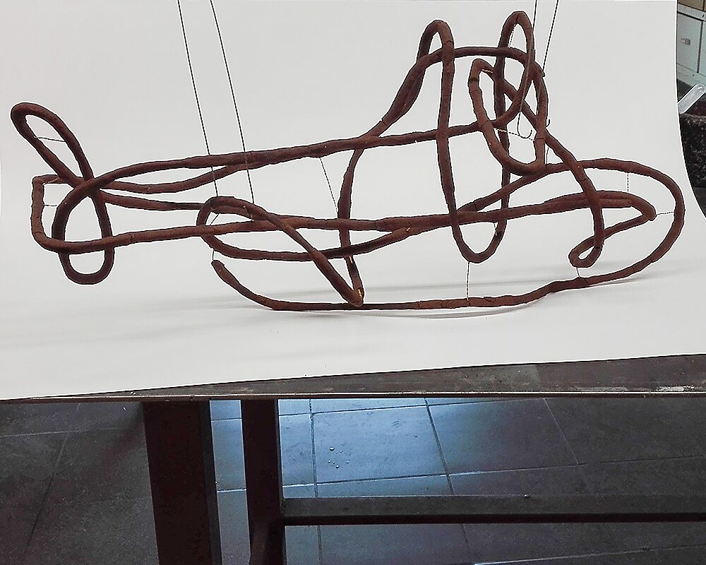 Shipbuilding — opstelling van het werk waarbij de langgerekte sculptuur horizontaal hangt voor een witte achtergrond.