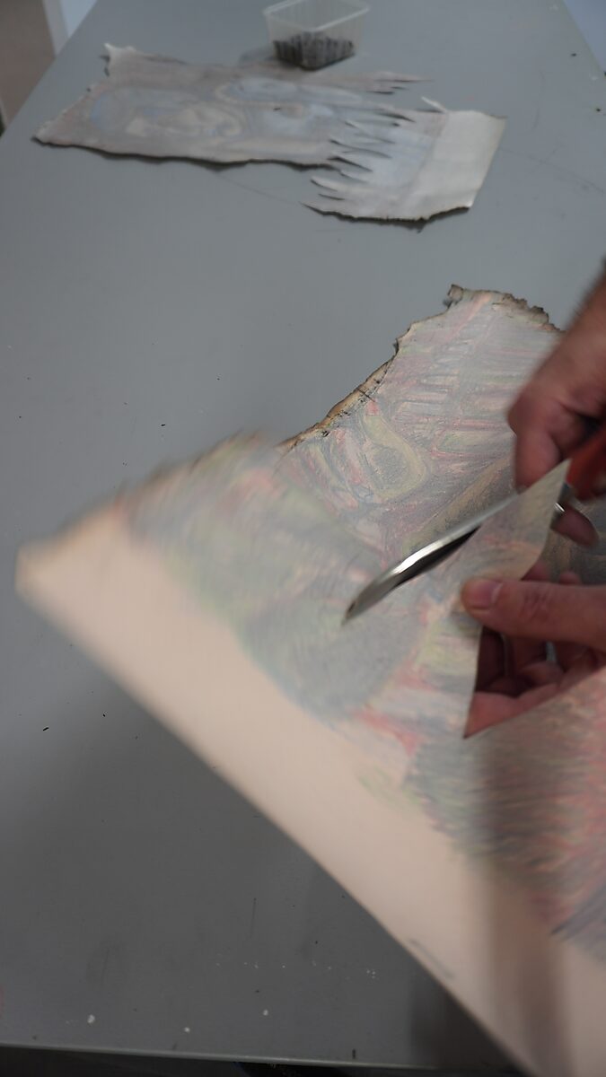 Benoemens-waardvlinders — Naming–Value Butterflies — proces tekening: Hangende man (1995) — handen knippen met een schaar een grillige rand uit het verbrande papier terwijl een tweede fragment op tafel ligt.