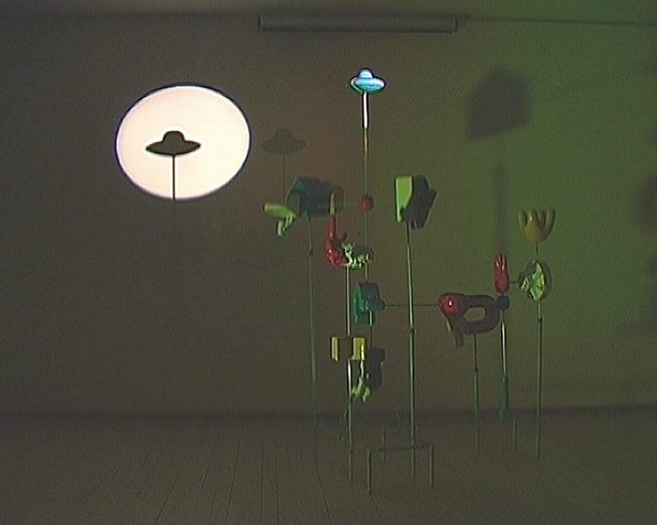 Choose and Change, Unidentified Arcade — photos of the installation and display: installation with multiple suspended objects, illuminated by a large circular projection with a UFO silhouette on the wall.