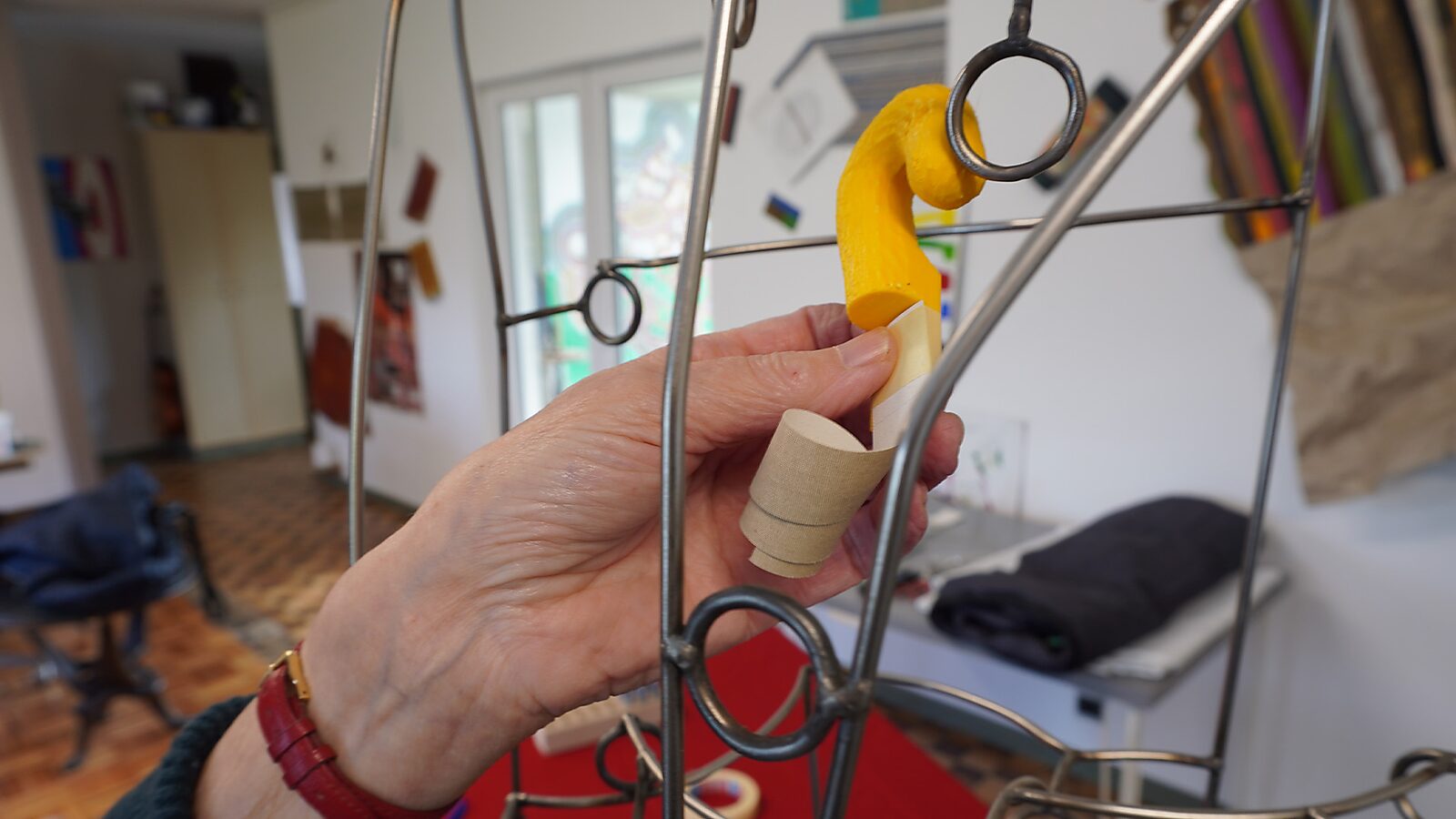 Sfincterman nr.0.0 — videostill handeling: het object wordt aan een metalen ring bevestigd, terwijl de papieren strook naar beneden hangt en opgerold is aan het uiteinde.