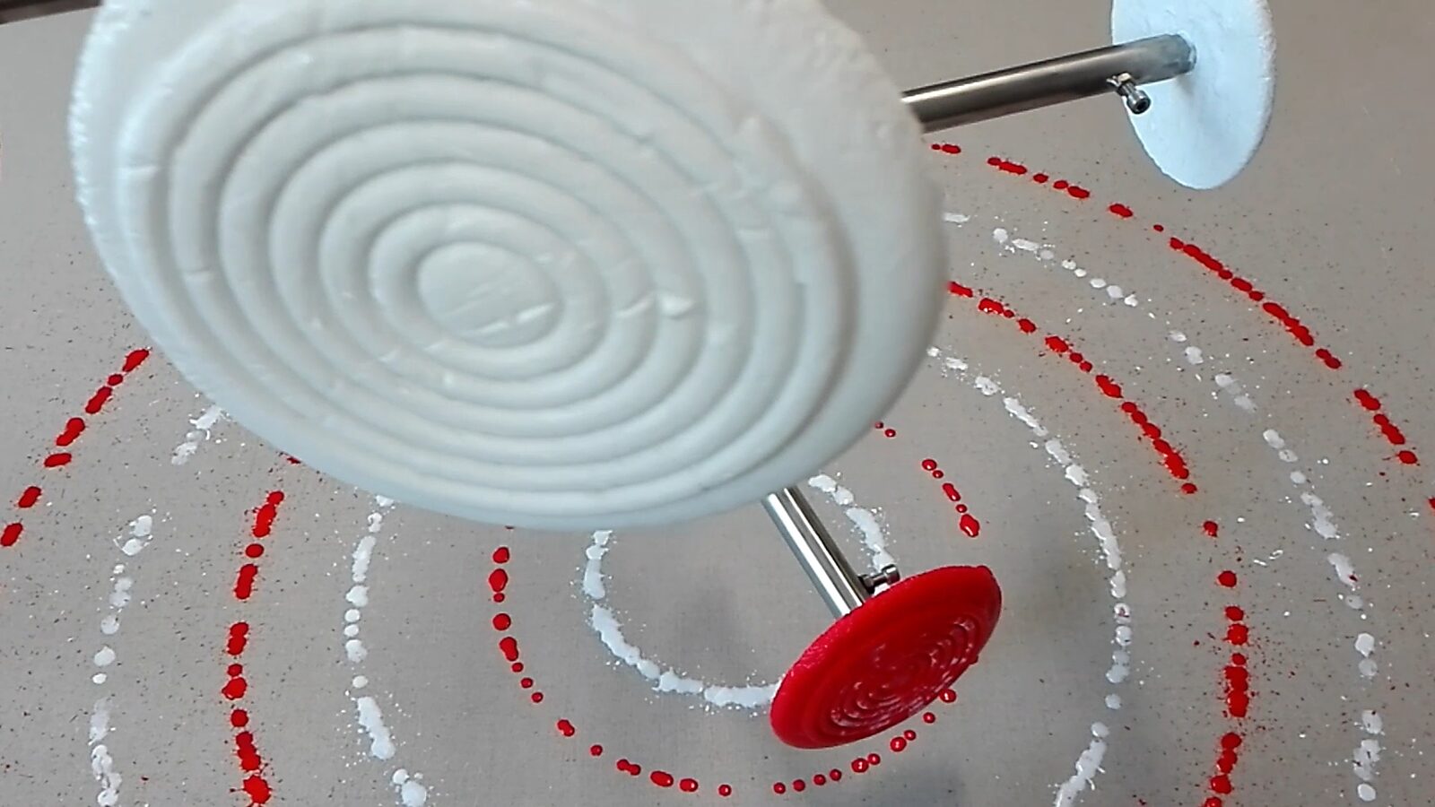 Smeltende doelen nr. 3 — videostill met close-up van een wit ijsdoel terwijl druppels verf cirkelvormige patronen op het doek achterlaten.