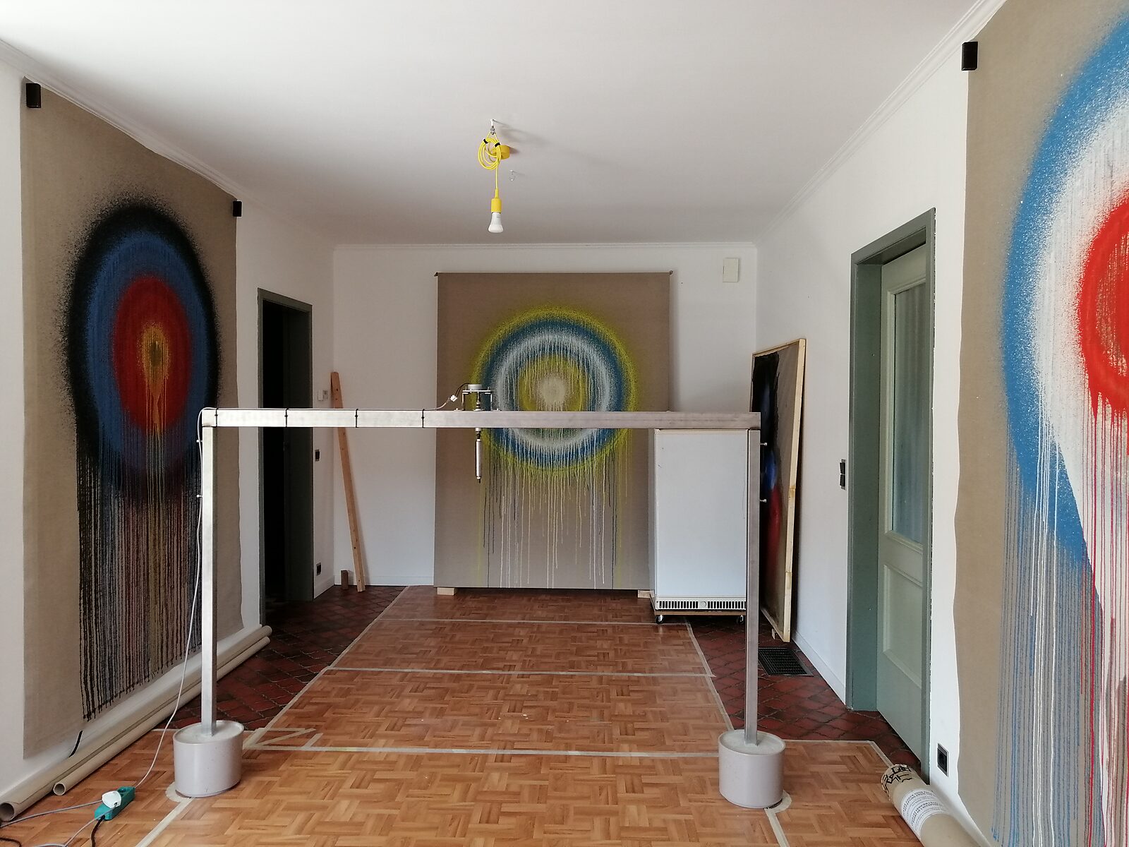 Smeltende doelen nr. 3 — atelieropstelling met metalen constructie voor roterende ijsdoelen voor een groot doek met concentrische verfkringen.