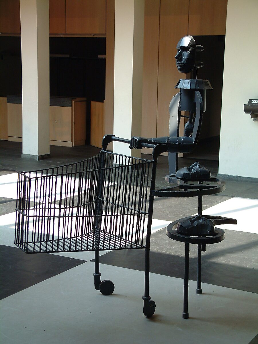 ‘Ode to Saturn’: Black metal figure with shopping cart and circular discs; sculpture in welded steel plate, CC De Adelberg, Lommel, 2003.