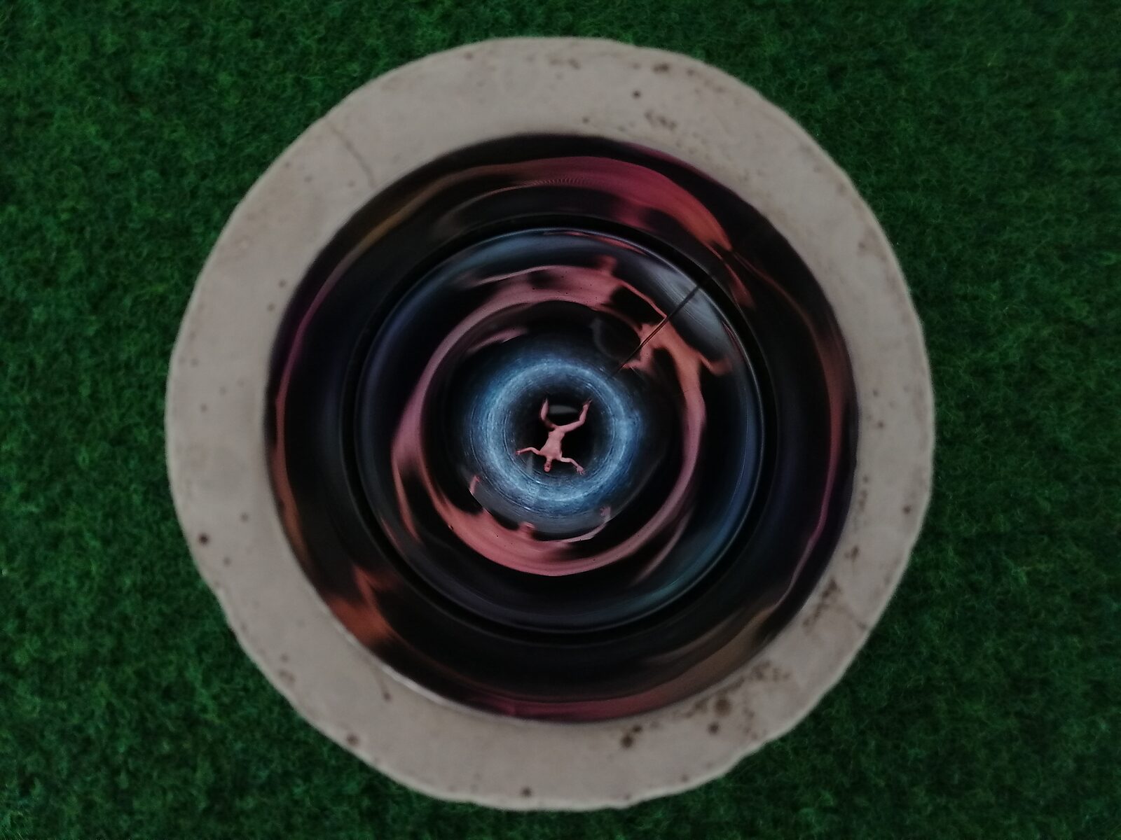 Well of Fluid Identities — view inside the well with reflective walls where rotating colour fields reveal a small human figure deep within the shaft.