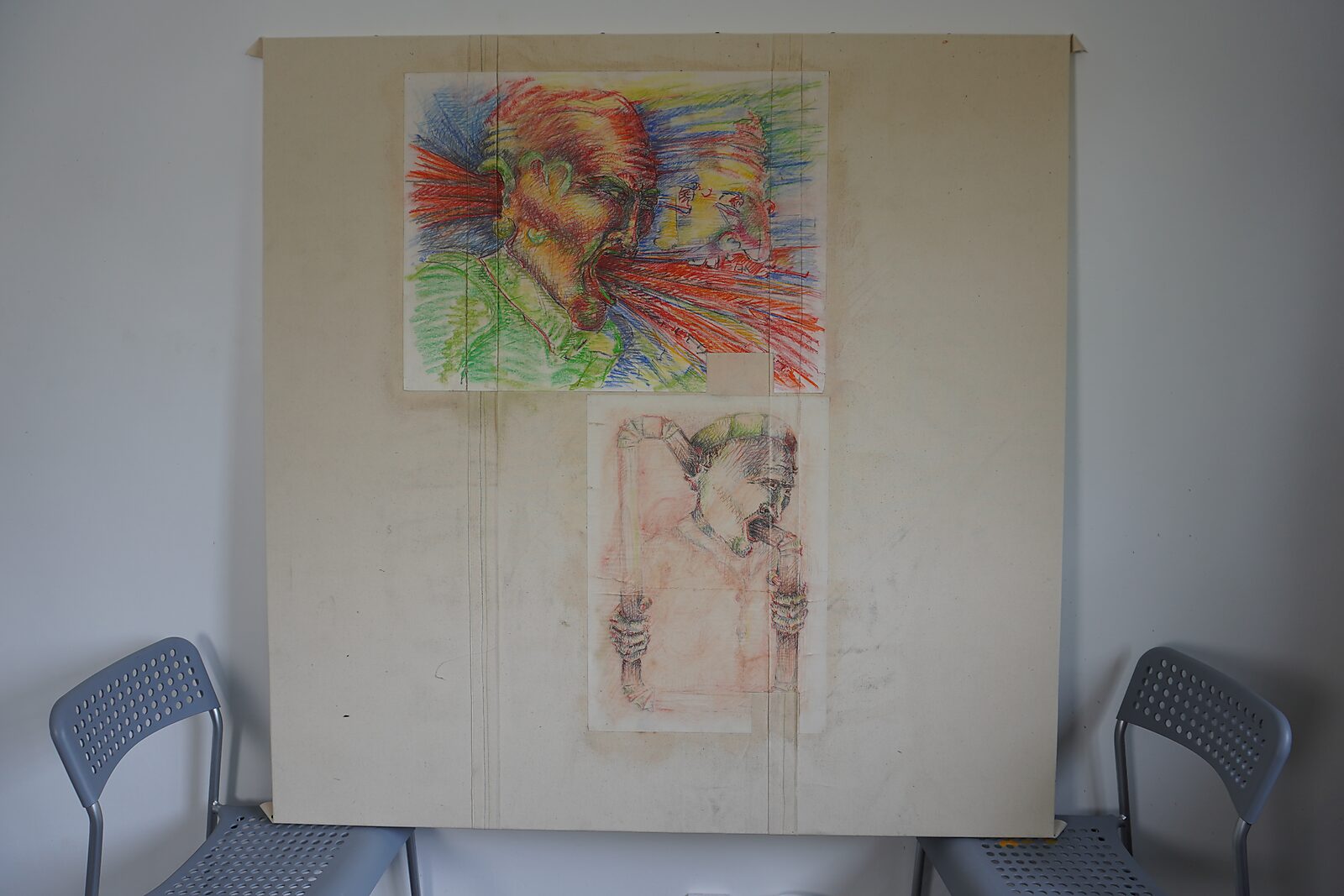Werkpaneel met twee expressieve tekeningen op papier bevestigd op een groot bord tussen twee stoelen; bovenaan een kleurrijke schreeuwende figuur, onderaan een lichtere schets van een figuur achter een kader.