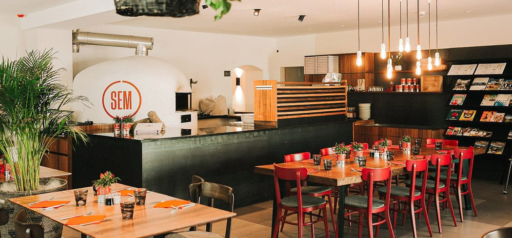 Moderner Gastraum der Pizzeria SEM in Töll bei Partschins mit großem Holzofen, warmem Licht und lockerer Bistro-Atmosphäre nahe Meran.