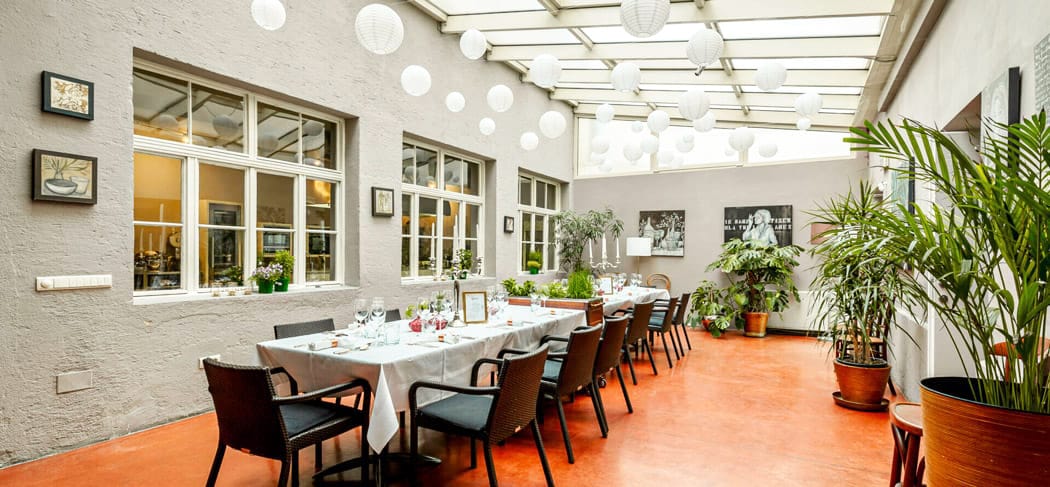 Condito Bolzano: location per eventi con interni eleganti, tavoli imbanditi, tetto in vetro e lanterne sospese – un ambiente moderno per feste ed eventi culinari