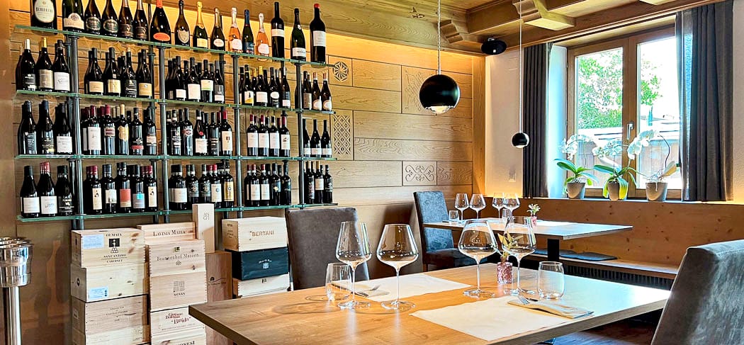 Steakhouse Anny in Marling mit stilvoller Weinwand, modern gedeckten Tischen, warmem Holzinterieur und hellem Fensterplatz mit Orchideen – elegantes Genussambiente.