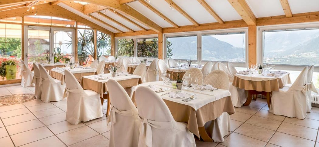Heller, elegant gedeckter Speisesaal im Restaurant Pichler in Schenna mit Panoramablick auf die Südtiroler Bergwelt – stilvolles Ambiente für Genießer.