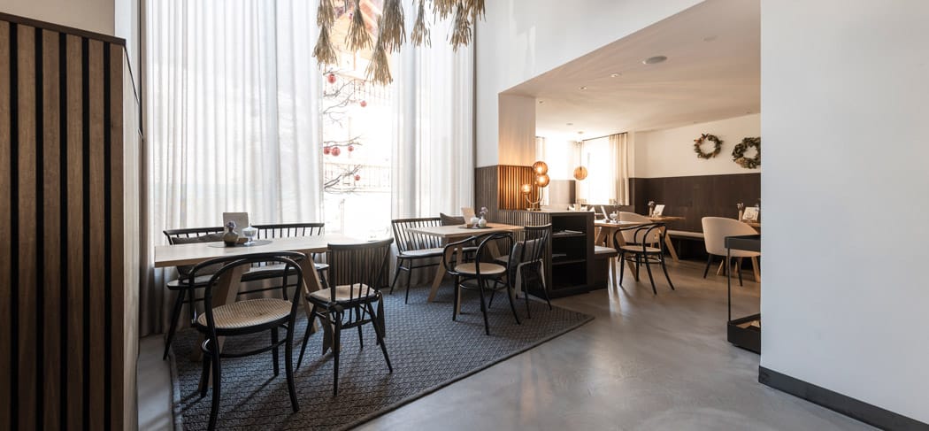 Das modern gestaltete Kobler Bistro & Café in St. Leonhard mit großen Fenstern, hellem Tageslicht, Naturmaterialien und stilvoller Einrichtung – ideal zum Frühstücken und Verweilen.