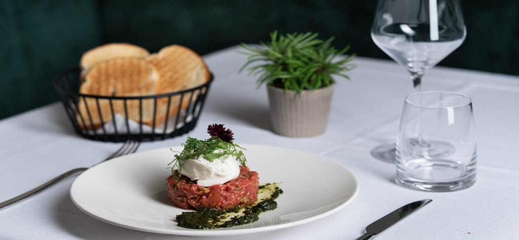 Genuss im Restaurant Ban Max in Truden: stilvoll gedeckter Tisch mit Pasta, Salat, Fleischgericht und Wein – italienische Küche in Südtirol.