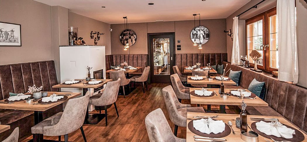 Sala da pranzo luminosa ed elegantemente arredata del ristorante Pichler a Scena, con vista panoramica sulle montagne dell’Alto Adige: un ambiente raffinato per i veri buongustai.