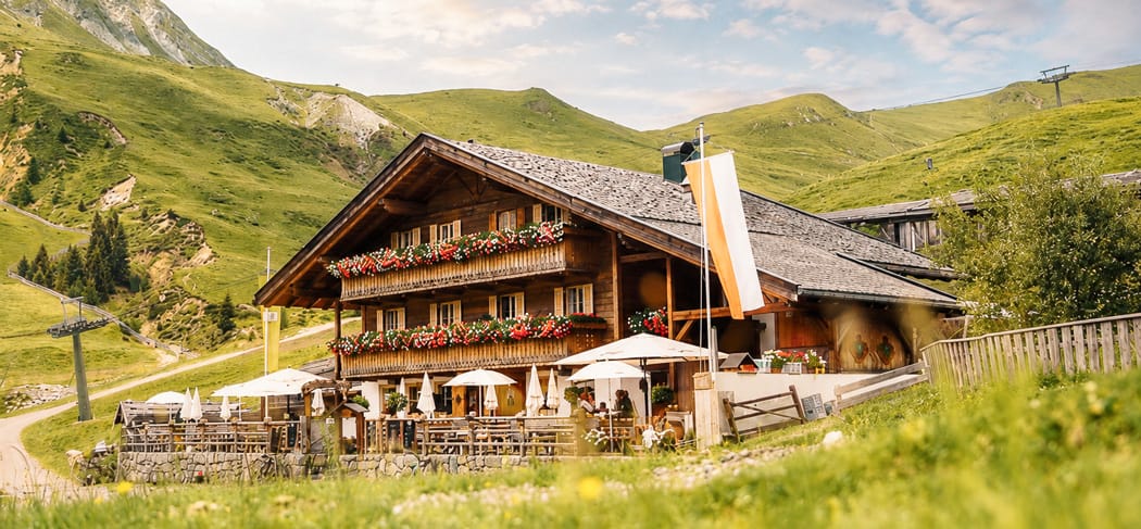 La Malga Kirchsteiger presso Merano 2000 con terrazza soleggiata, balcone fiorito e cavalli avelignesi – circondata da prati alpini e cime, ideale per escursionisti e buongustai.