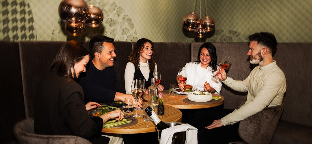Amici gustano aperitivi e piatti mediterranei al Café Bistro Emmi a Scena vicino Merano in un ambiente elegante in Alto Adige.
