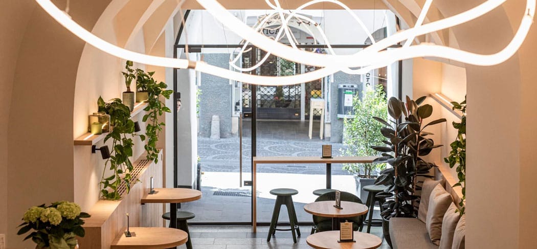 Modernes Ambiente im Arcus Bar & Café in Meran mit stilvoller Einrichtung, Pflanzen, gemütlichen Sitzplätzen und Blick auf die historischen Meraner Lauben.