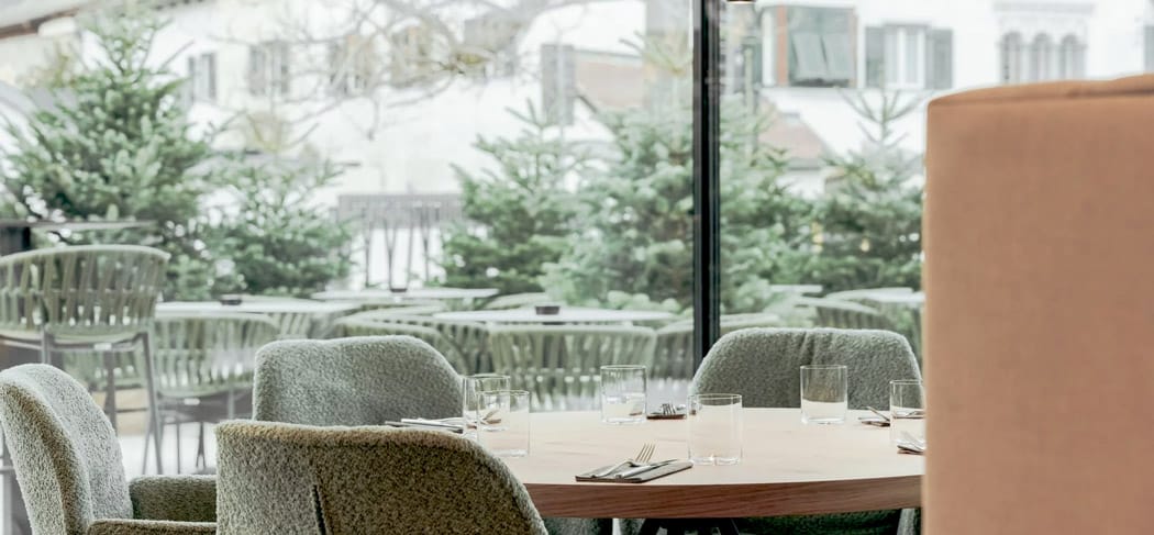 Tavolo apparecchiato con stile al ristorante Soley di Bressanone con vista sulla terrazza verde e sulle facciate del centro storico circostante: ambiente moderno e tranquillo.