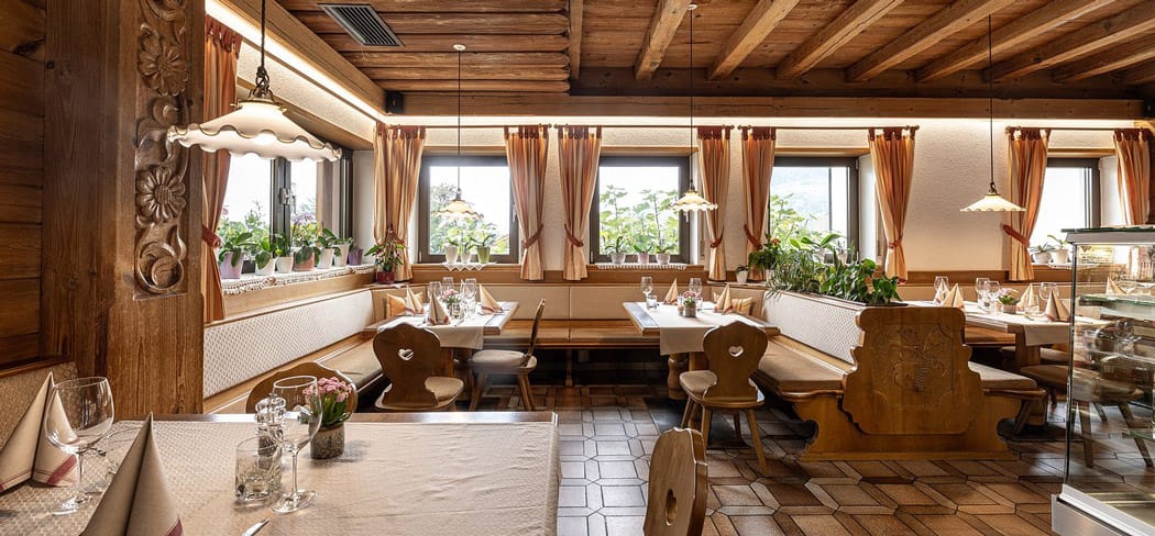 Gemütliches Südtiroler Restaurant mit Holzdecke, traditionellen Eckbänken, dekorativen Vorhängen und liebevoll gedeckten Tischen in der Garberstub in Partschins