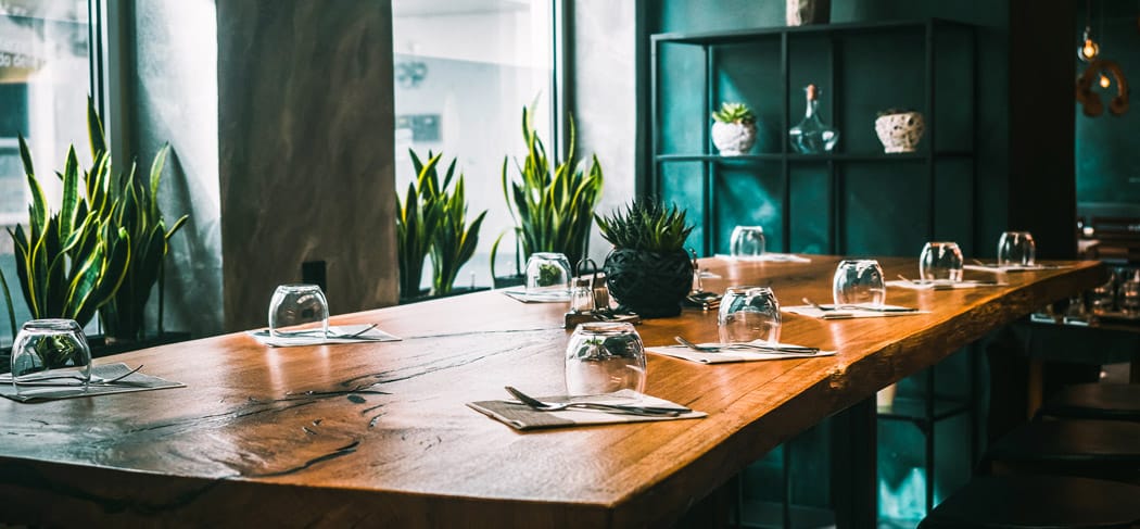 Il ristorante Agorà 21 a Bressanone, arredato in stile moderno, con eleganti tavoli in legno, piante verdi e un'atmosfera accogliente, è il luogo ideale per gustare tapas, pizza e ottimo cibo in Alto Adige.