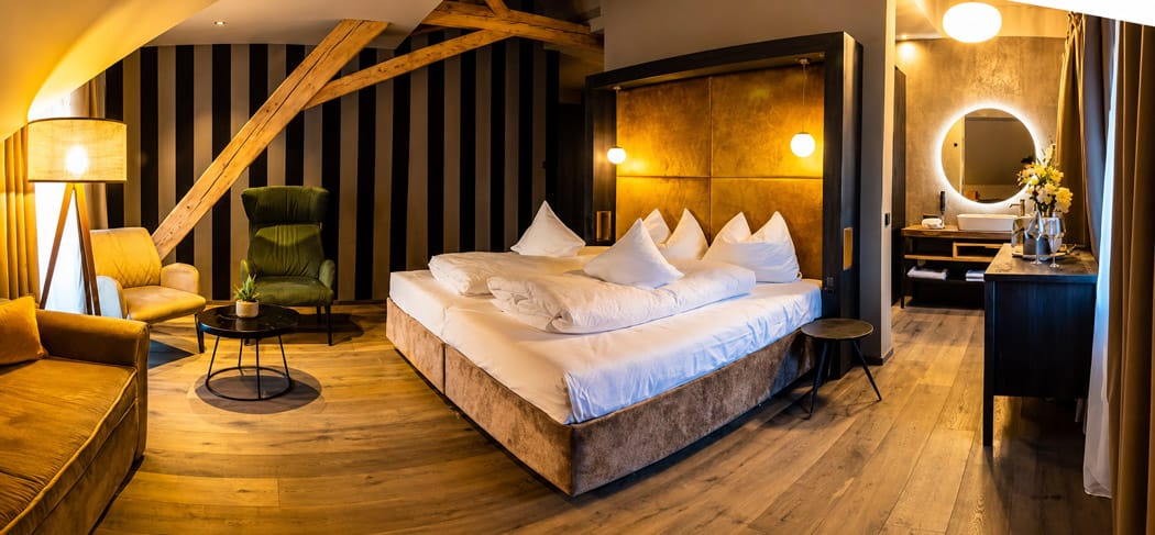 Elegante suite in un hotel della Val d'Ega, nei pressi di Bolzano, caratterizzata da un design moderno, luci calde, un accogliente salotto e un bagno di classe.