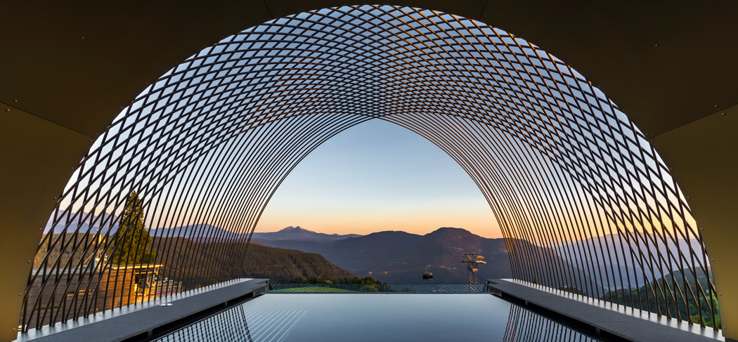 Gloriette Guesthouse sul Renon, con piscina a sfioro, architettura spettacolare e vista panoramica sulle montagne altoatesine al tramonto.