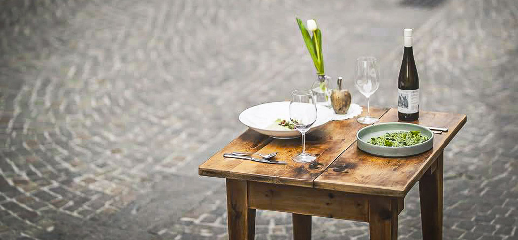 Genuss im Restaurant Ban Max in Truden: stilvoll gedeckter Tisch mit Pasta, Salat, Fleischgericht und Wein – italienische Küche in Südtirol.