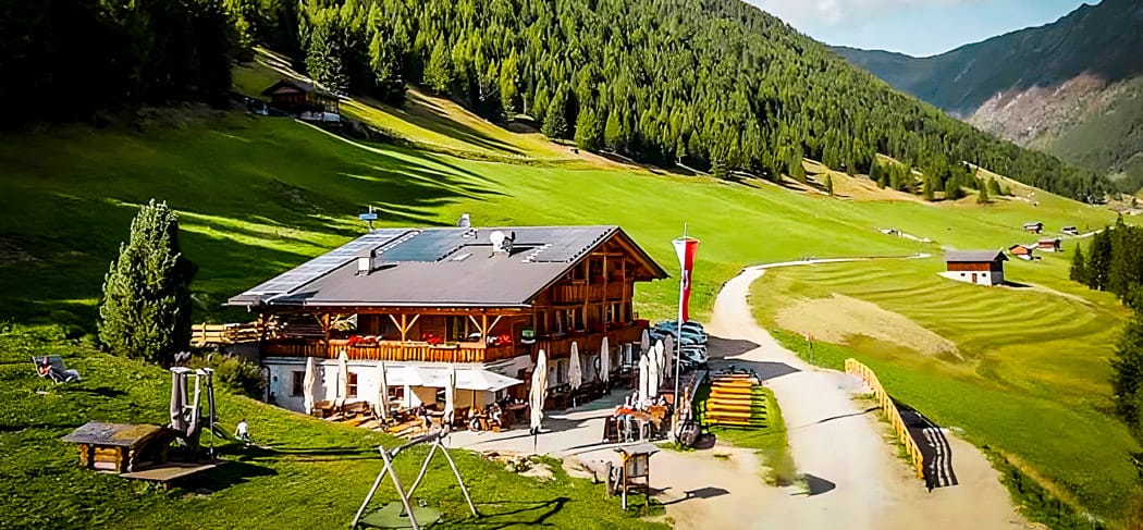 Die Großberghütte im sonnigen Altfasstal oberhalb von Meransen – umgeben von grünen Wiesen, Bergen und Wäldern, idealer Ort zum Wandern und Genießen in Südtirol.