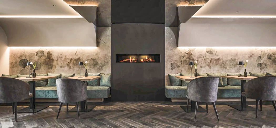 Lounge im Restaurant SomVino in Dorf Tirol mit Kamin, eleganten Sitznischen und warmem Licht, stilvolles Ambiente für genussvolle Abende in Südtirol
