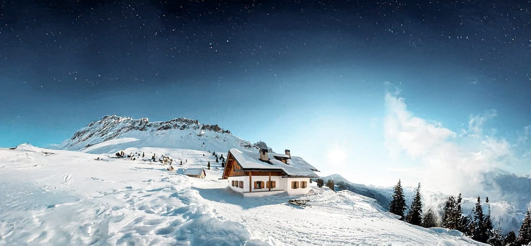 Verschneite Gampenalm im Villnösstal bei Nacht, unter klarem Sternenhimmel mit Blick auf die Dolomiten im Naturpark Puez-Geisler.