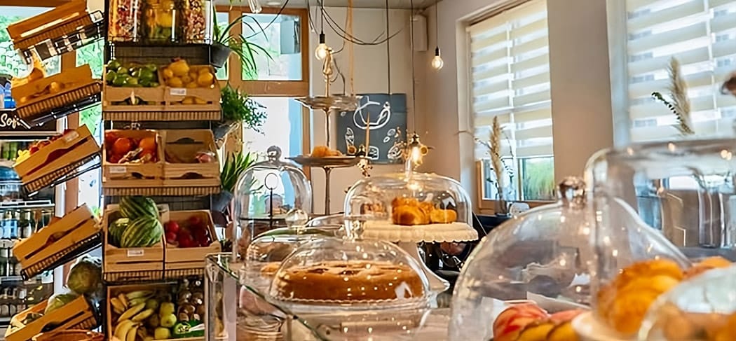 Uno sguardo all'interno dello Stabner Postlodn con frutta fresca, dolci sotto campane di vetro e interni arredati con cura: un accogliente mix tra bar e negozio.