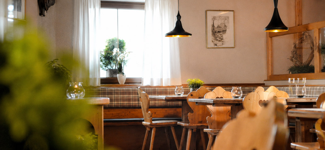 Accogliente sala da pranzo del Ristorante & Caffè Cutraun a Parcines, con arredi tradizionali in legno, atmosfera calda e ospitalità altoatesina.