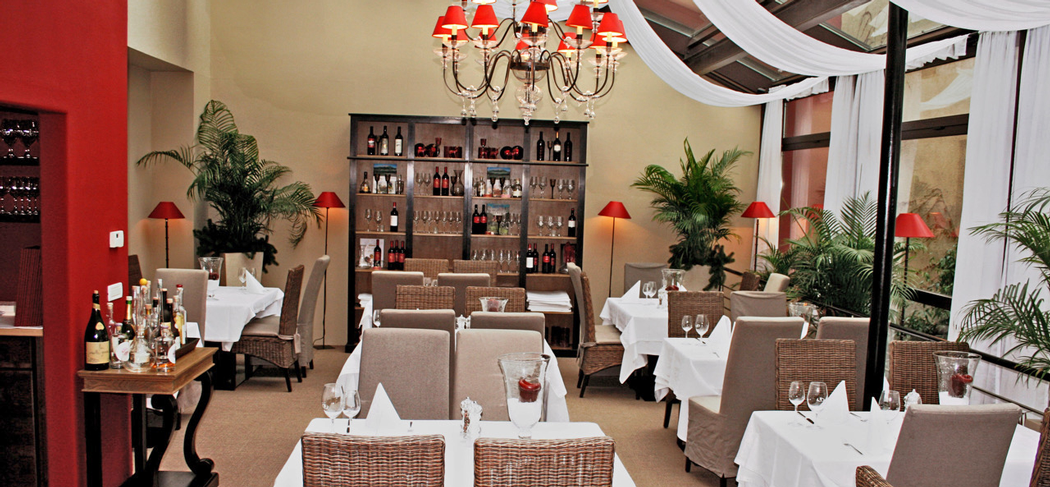 Elegante sala interna del Bistro Seven a Merano con tavoli apparecchiati, lampadari rossi e atmosfera mediterranea sotto gli storici Portici.