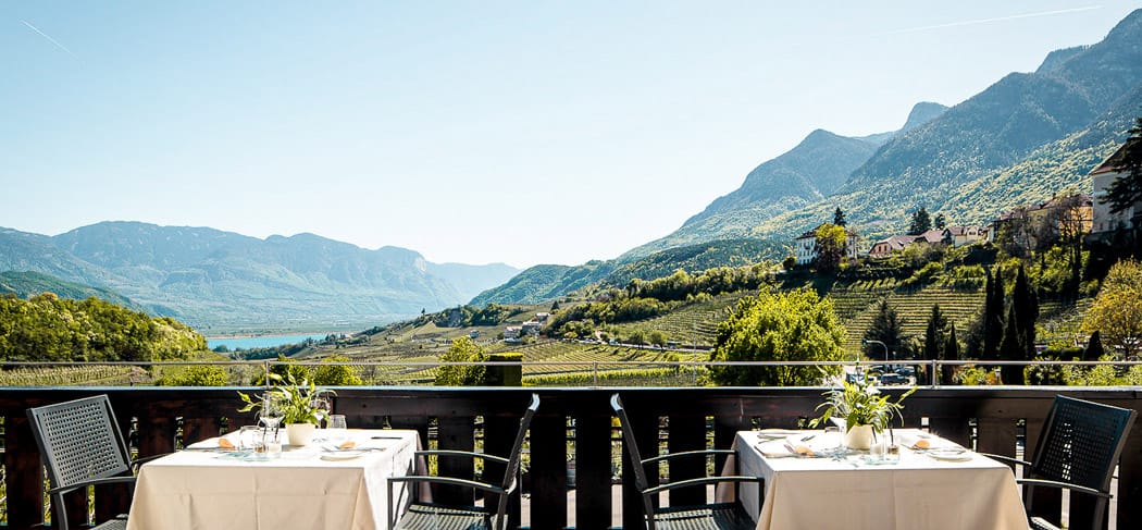 Vista panoramica sui vigneti, sulle montagne e sul Lago di Caldaro dalla terrazza del ristorante Ritterhof a Caldaro: il luogo perfetto per un pasto delizioso in Alto Adige.