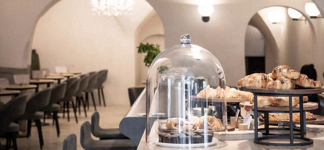 Elegante Adler Tagesbar in Brixen mit frischem Gebäck, stilvollem Interieur, Gewölbedecke und gemütlicher Atmosphäre für Frühstück, Kaffee und Genussmomente.