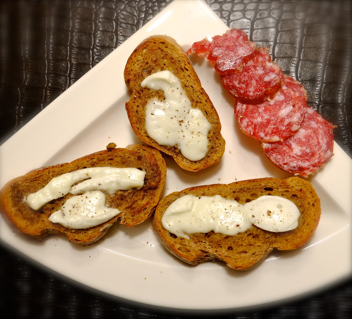 Zwischengang Roggen-Crostini mit Sardellen-Butter, Büffel-Mozarella + Trüffel-Salami