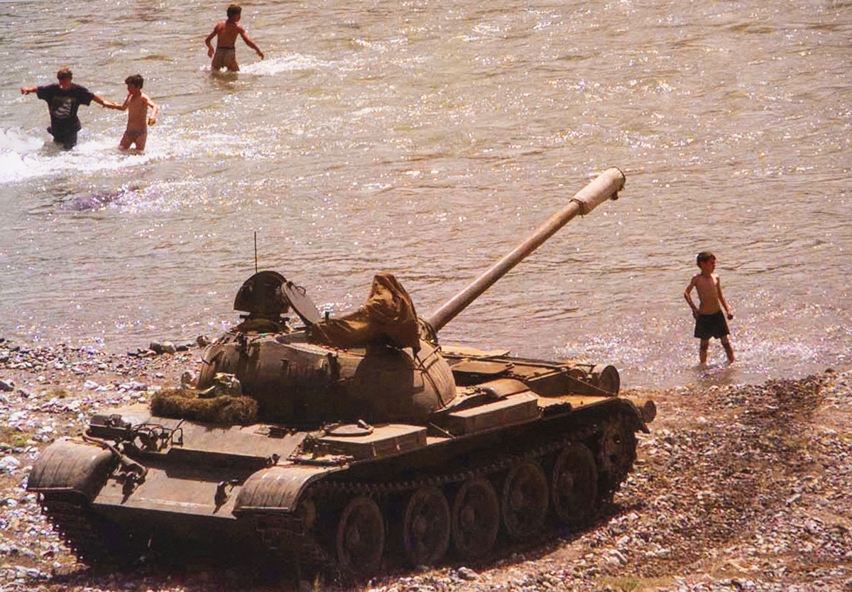 Ein Panzer der albanischen Armee steht am Ufer eines kleinen Sees in der Nähe von Kukes,Albanien, wo albanische Flüchtlinge den Beginn des Sommers genießen,am 6.Juni 1999