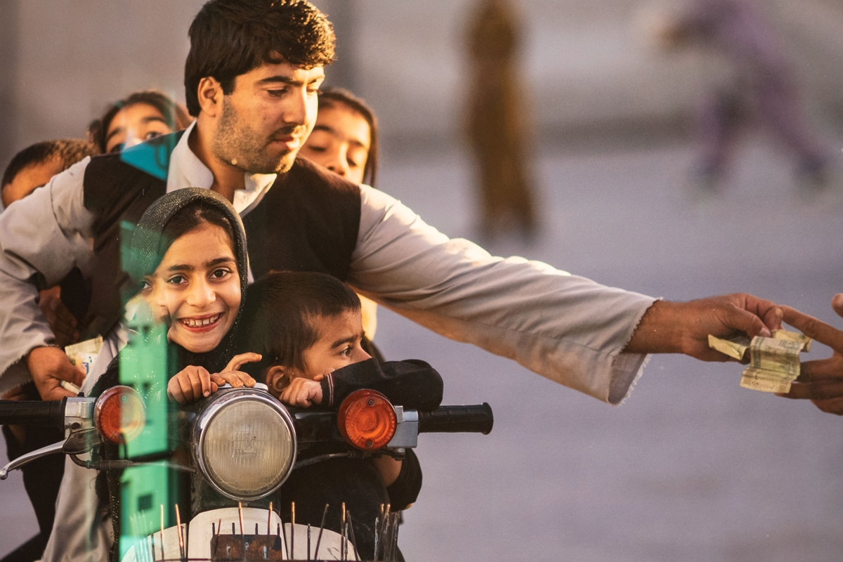 Ein afghanischer Mann mit seinen fünf Kindern auf seinem Motorrad zahlt Geld für den Eintritt in einen Park in Kandahar, Afghanistan, am 1.November 2013