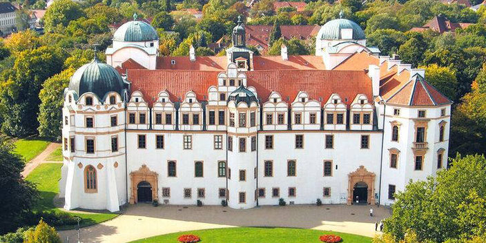 Schloss Celle aus der Vogelperspektive im Sommer. Schönes Barockschloss, quadratisch mit 3 patinierten Kuppeltürmen und rotem Pfannendach. 