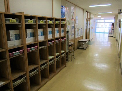職員室前廊下(１階)左の棚は学級ごとの配布物入れです。