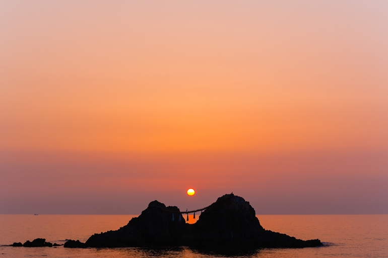写真：夫婦岩（伊勢）の間から昇る夏至の朝日