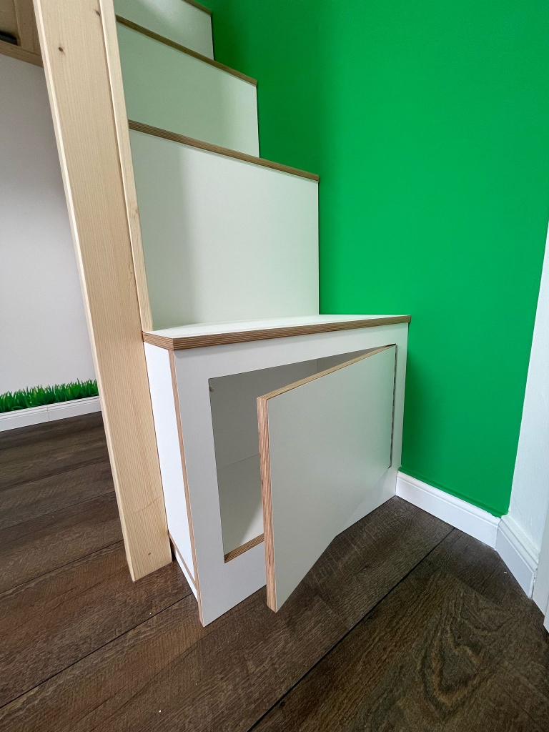 Hochebene mit Treppe und Stauraum, verspieltes Design und Bullaugenfenster, Nahaufnahme auf Stauraum unterhalb der Stufen