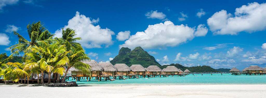 Tropische Lagune mit Overwater-Bungalows, Palmenstrand und Bergkulisse