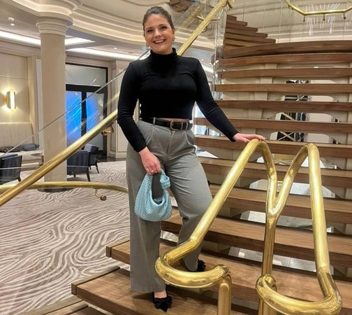 Anne Kessenich von Emocean Cruises steht auf der eleganten goldenen Treppe in der Lobby der Seven Seas Splendor