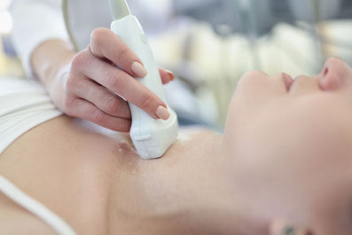 Ärztin berührt den Hals einer Patientin mit dem Ultraschall-Gerät 
